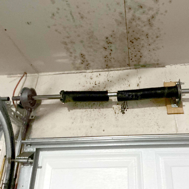 Broken single garage door torsion spring before replacement in Everman, Texas.