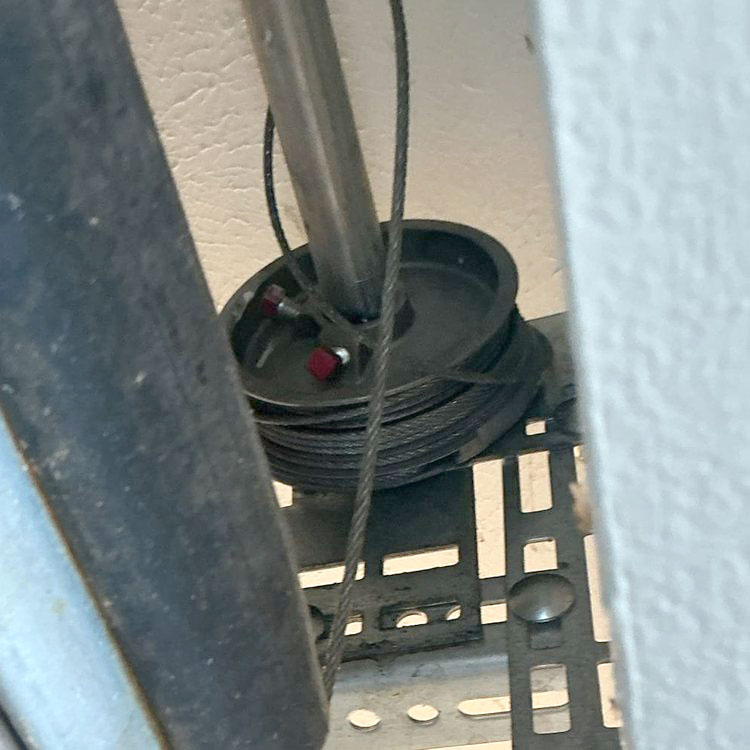 Garage door cable repair in Dallas, TX with new lift cables, premium rollers, and a replacement bottom bracket installed.
