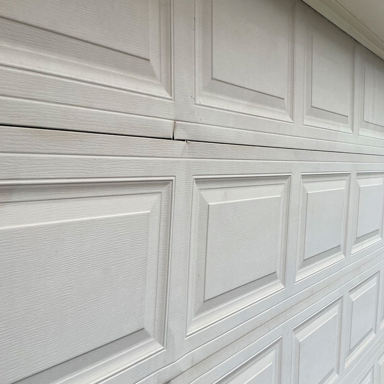Dented and cracked panels on an aging steel garage door before replacement in San Antonio, TX