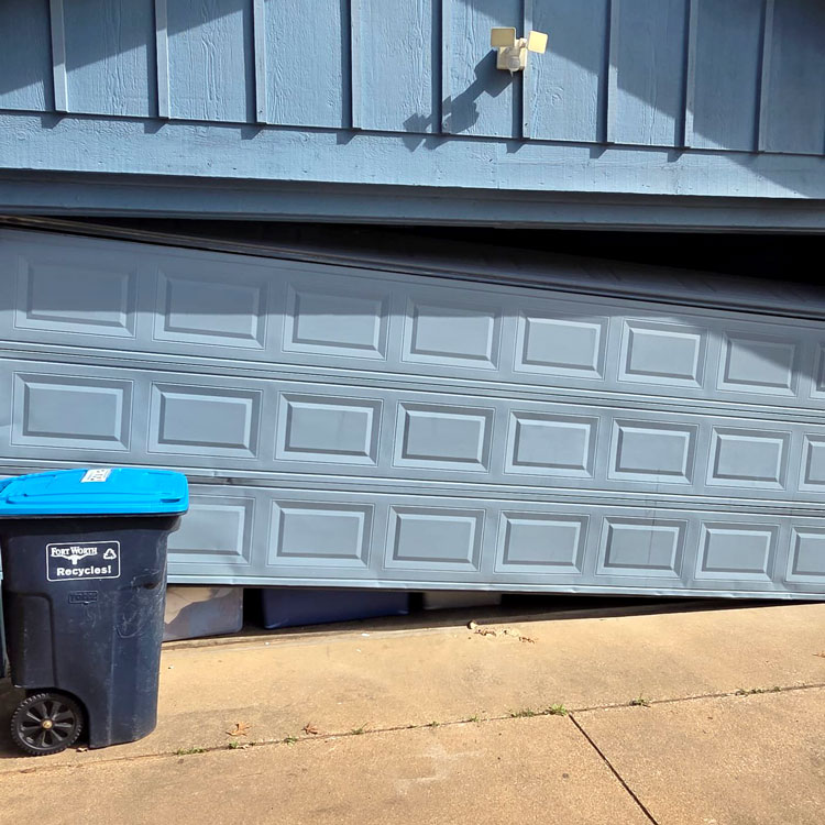 Garage door with a creased panel after coming off track before replacement in Fort Worth, Texas.