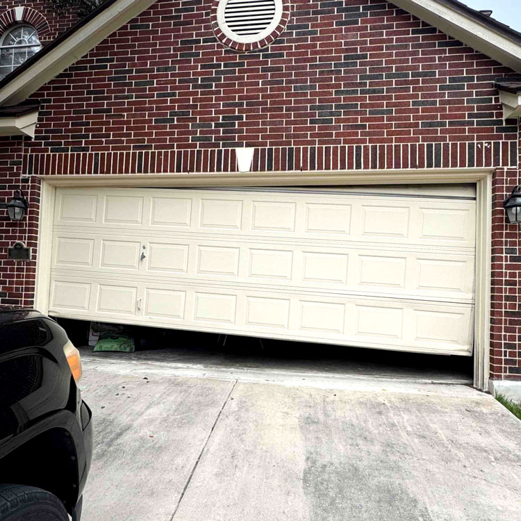 Crooked garage door hanging unevenly after coming off track at a San Antonio, TX home
