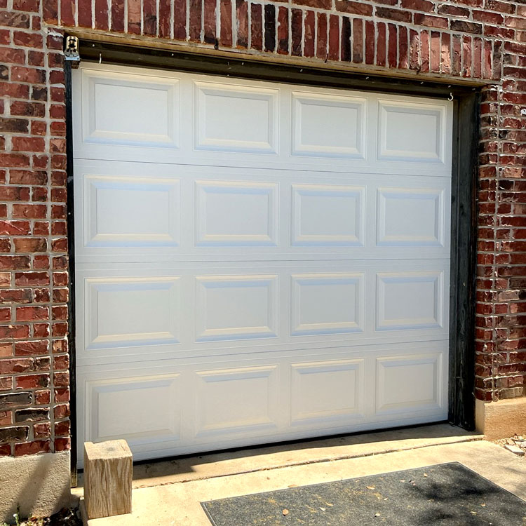 New white raised-panel garage door installed after the previous door sustained panel damage in San Antonio, TX